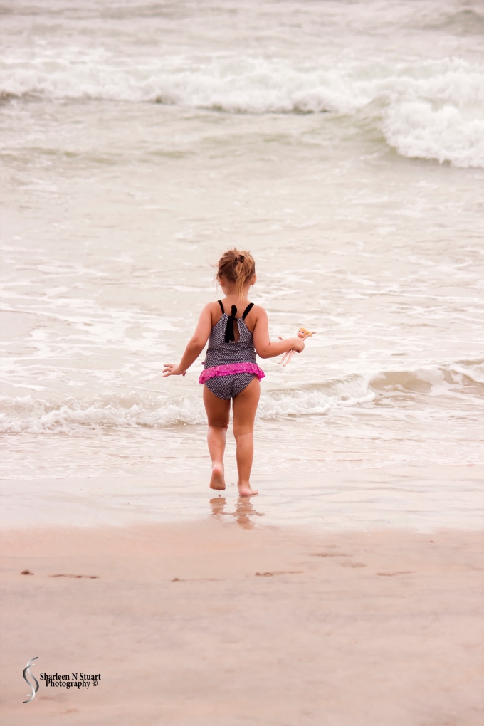 Little girl running into the waves